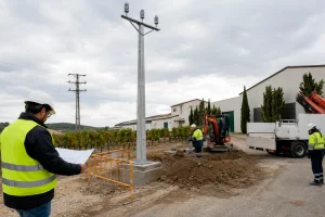 Técnicos revisando planos, topografía y cimentación de un poste de media tensión junto a las instalaciones de Vinícola Delgado.